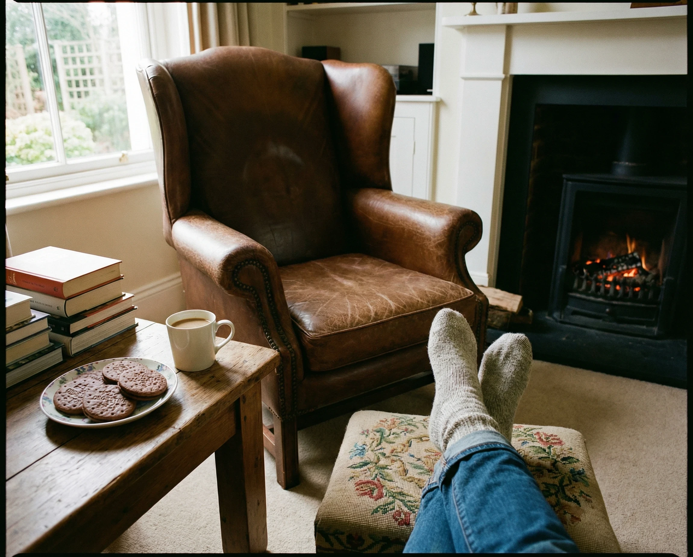 A restful scene showing someone with their feet up and a cup of coffee and chocolate biscuits on a small nearby table. 
