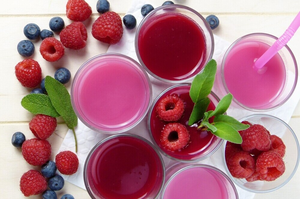 Pink and read smoothies in glasses with raspberries and blueberries