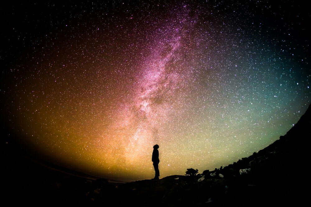 A silhouetted man staring at the vastness of the cosmos