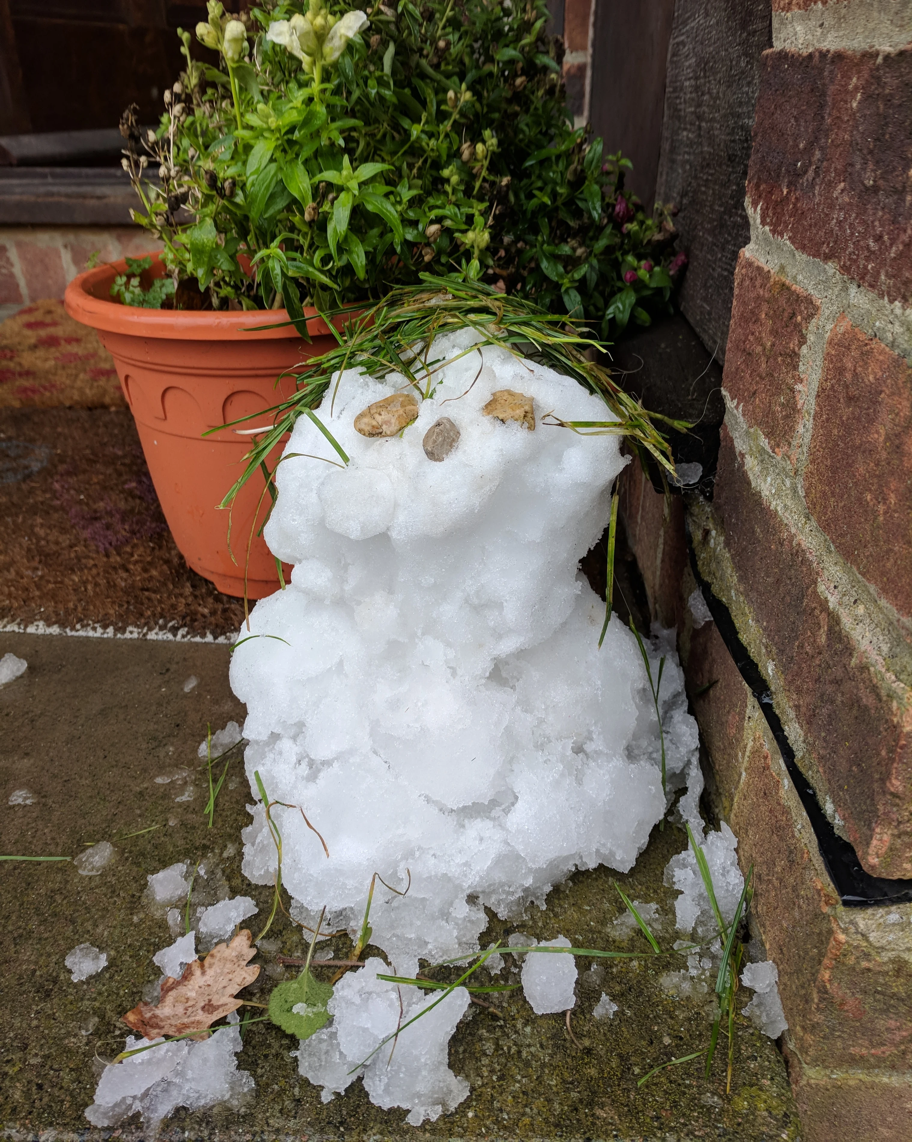a small snowman next to a plant pot