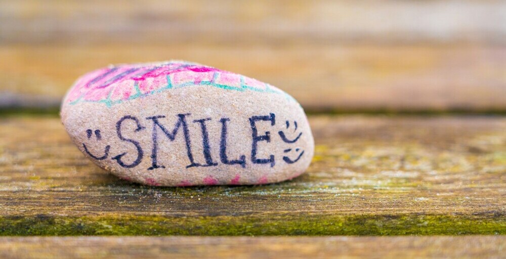 Image of a stone painted with the word 'smile'