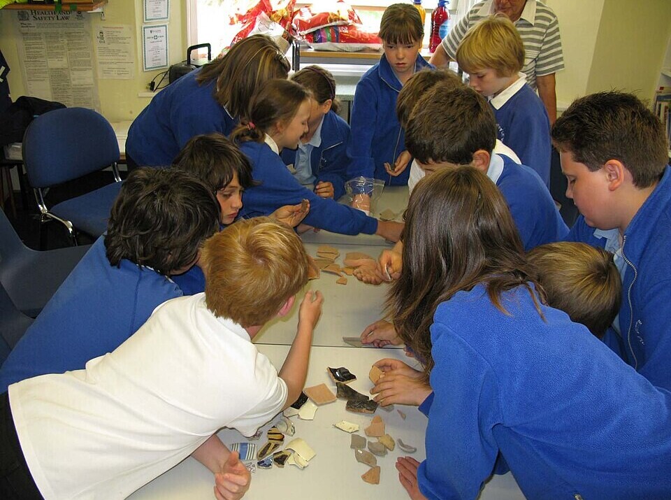children learning about archeology by looking at pottery pieces
