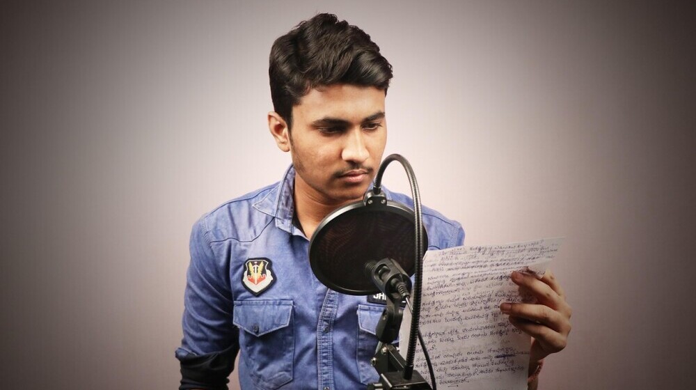 boy reading a script in front of a mic