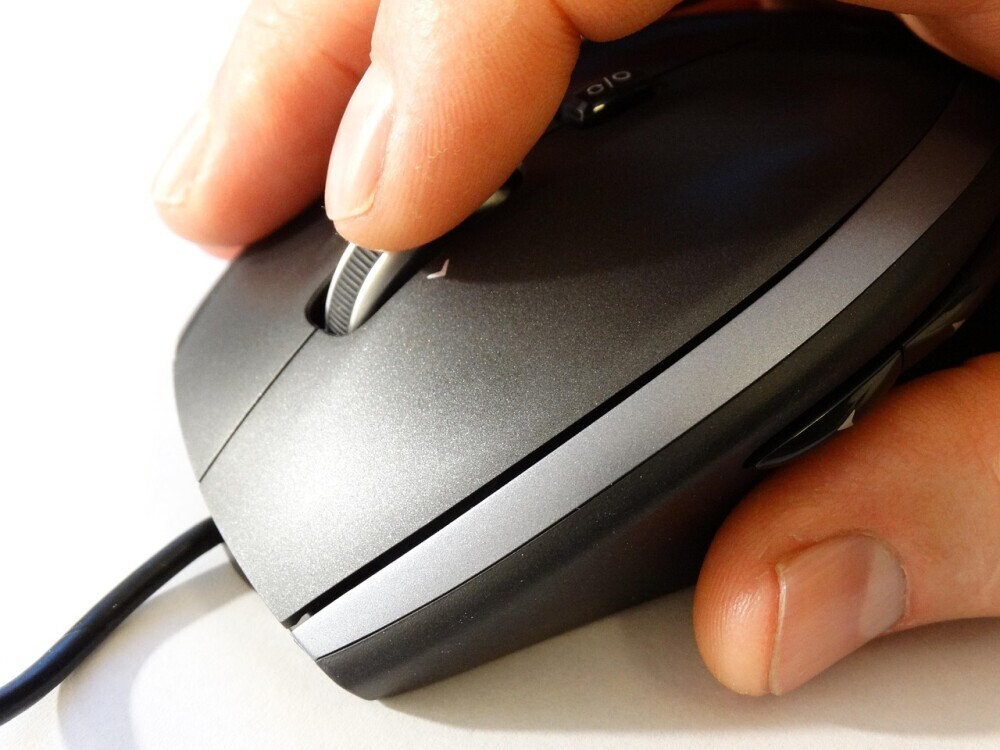 A hand placed on mouse scrolling and clicking.