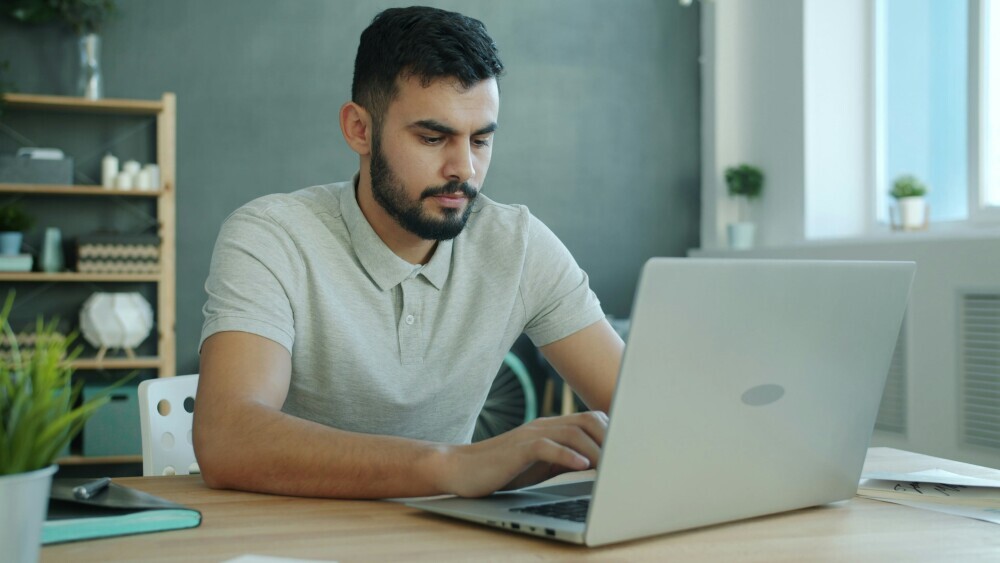 Affiliate marketer working with discipline on a laptop despite feeling tired, showing commitment and consistency in a focused workspace