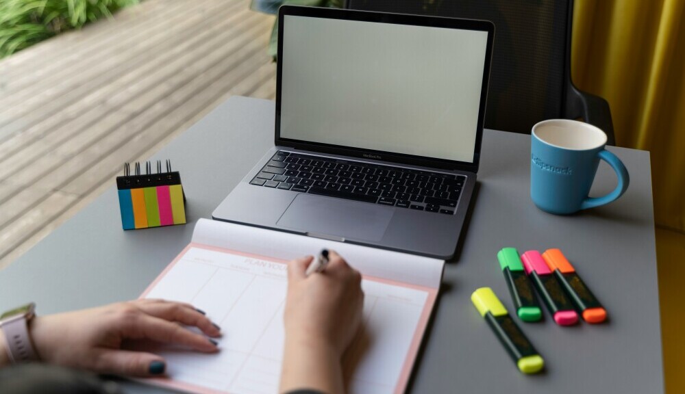 Affiliate marketer organizing tasks, content ideas, and workflow on a laptop and notebook in a clean and structured workspace
