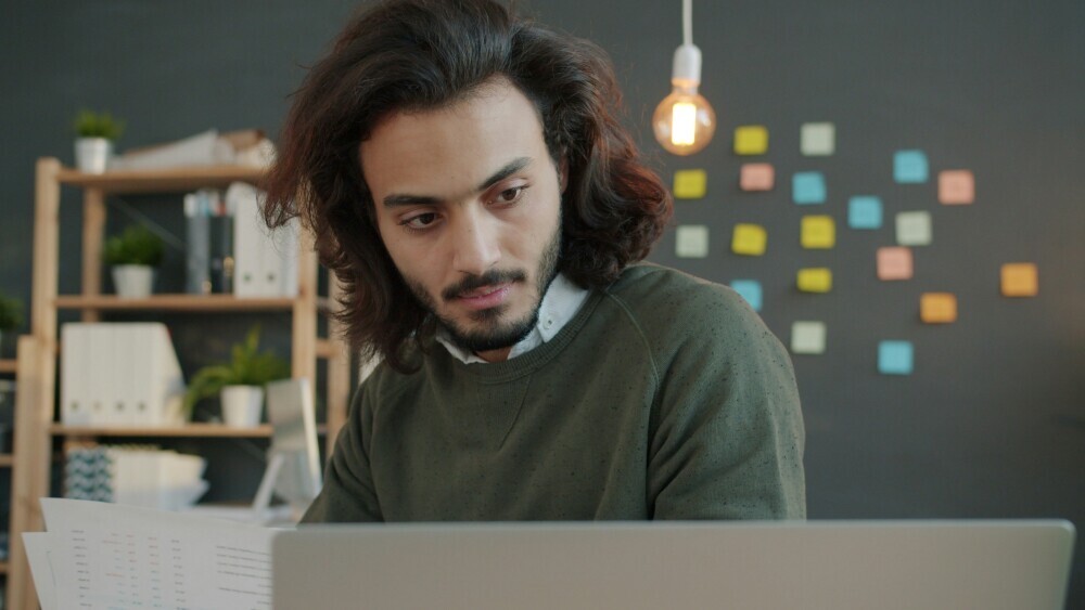 Affiliate marketer researching content ideas on a laptop, brainstorming topics with notes and keyword tools in a focused workspace