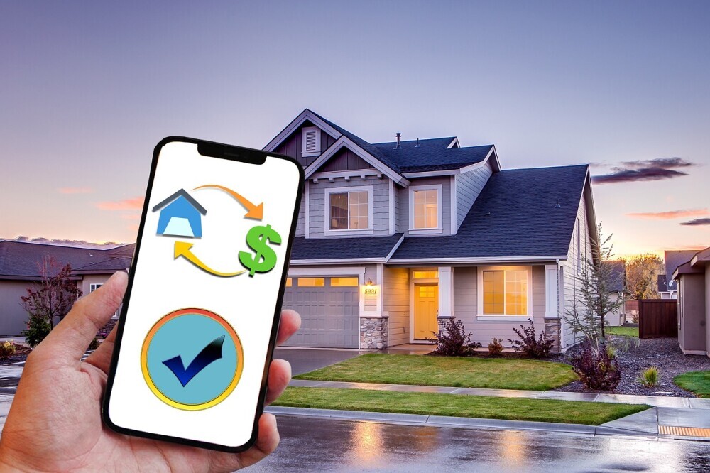 image of a beautiful home in the background of a person holding and show the phone screen showing the process of buying house and land.