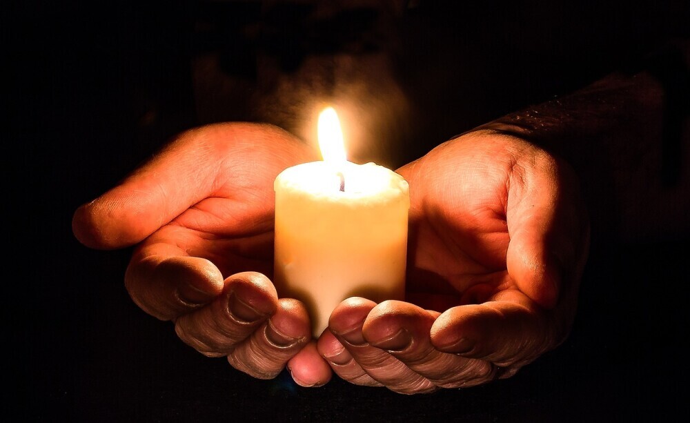 image of a person lighting up a candle placing on his hand to show that the that story of being free from the life of loneliness is like the light that can shine for others to see and glorify the name of the Lord.