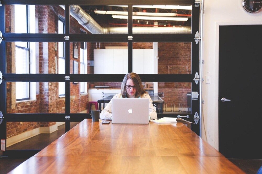A woman working on a computer from the comfort of her home checking her affiliate marketing sales.