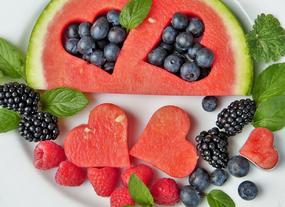 heart shapes cut out of a watermelon with blueberries inserted