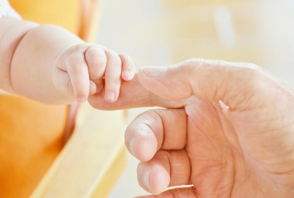 baby touching dad's hand