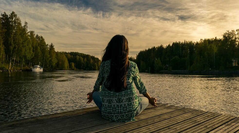 woman practicing mindfulness beside a lake