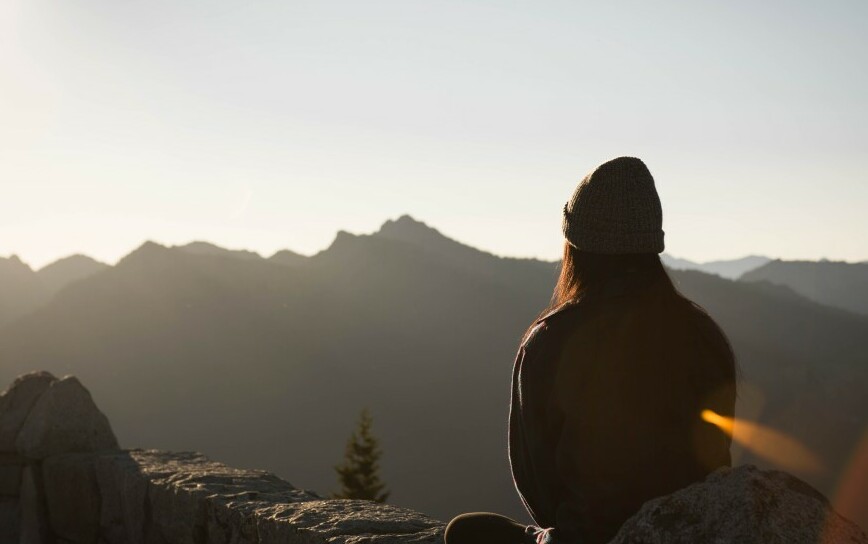 young woman meditating facing mountains