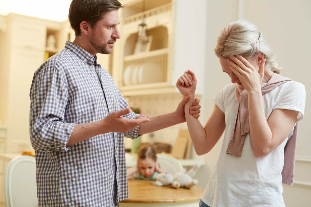 couple arguing; man grabbing wife's arm