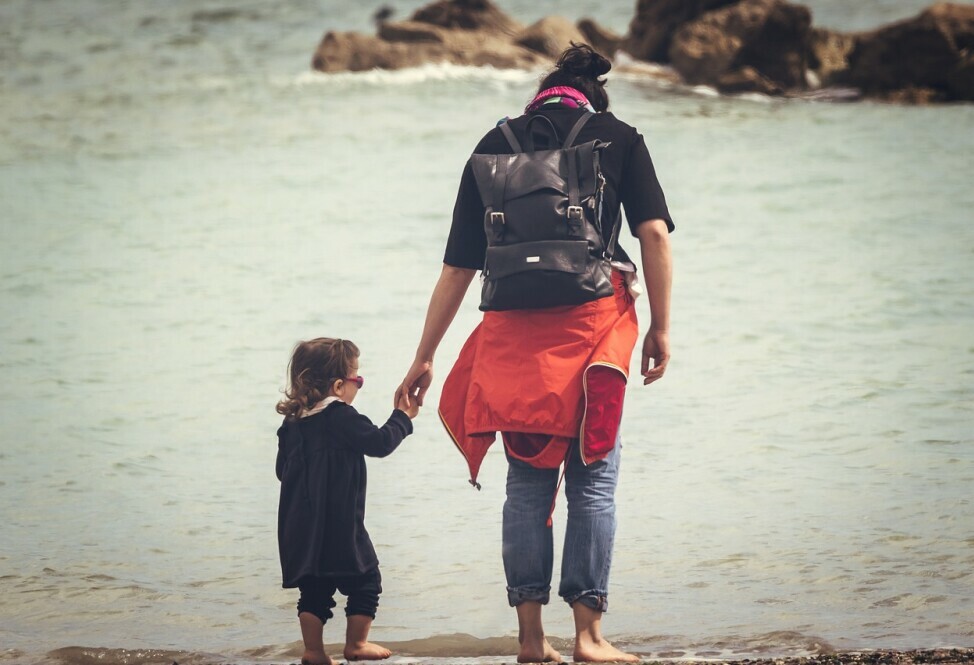 father with young daughter walking on a beach