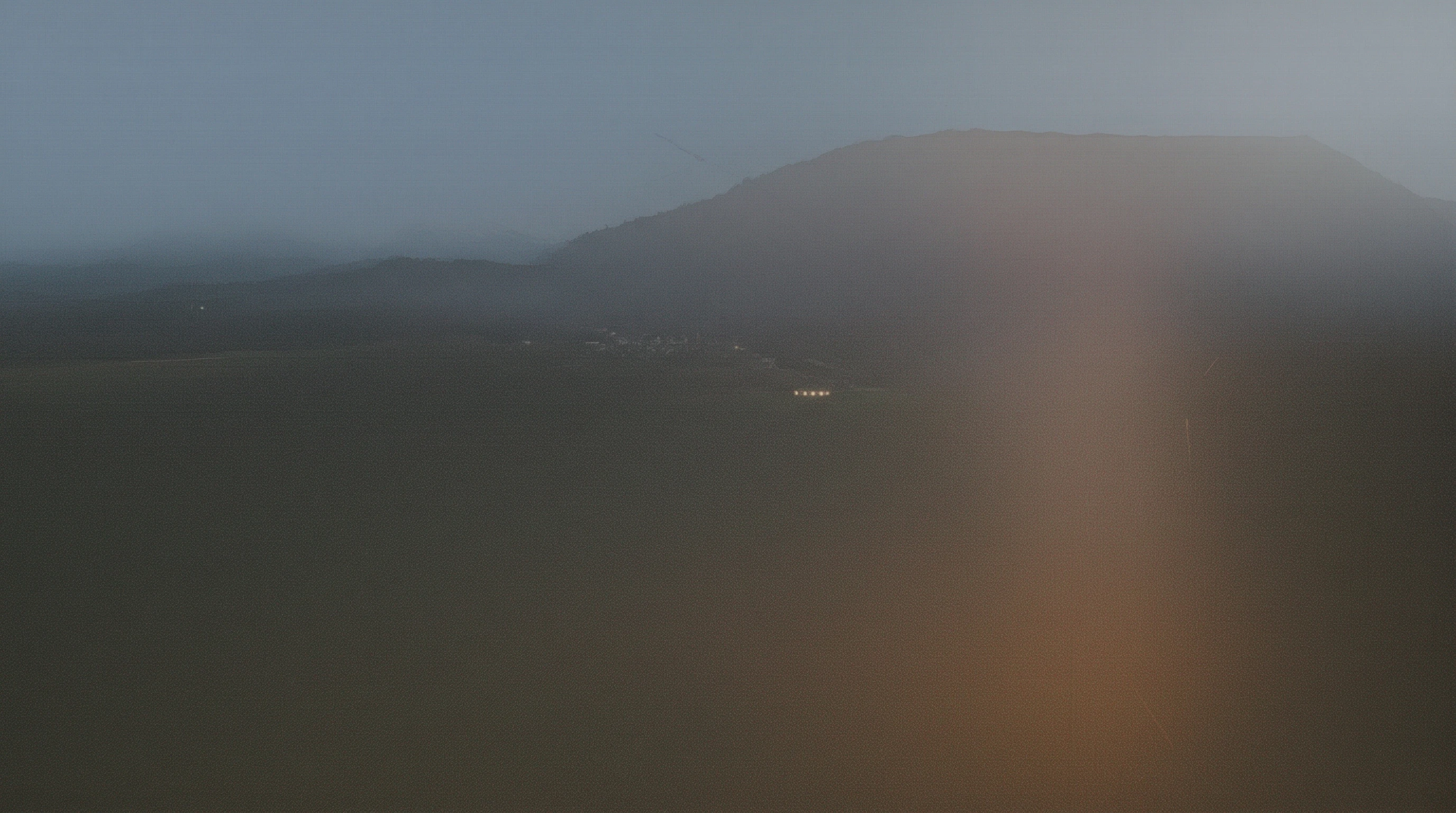 Bonfire blazing at dusk in the Slovenian countryside, surrounded by rolling hills and forests