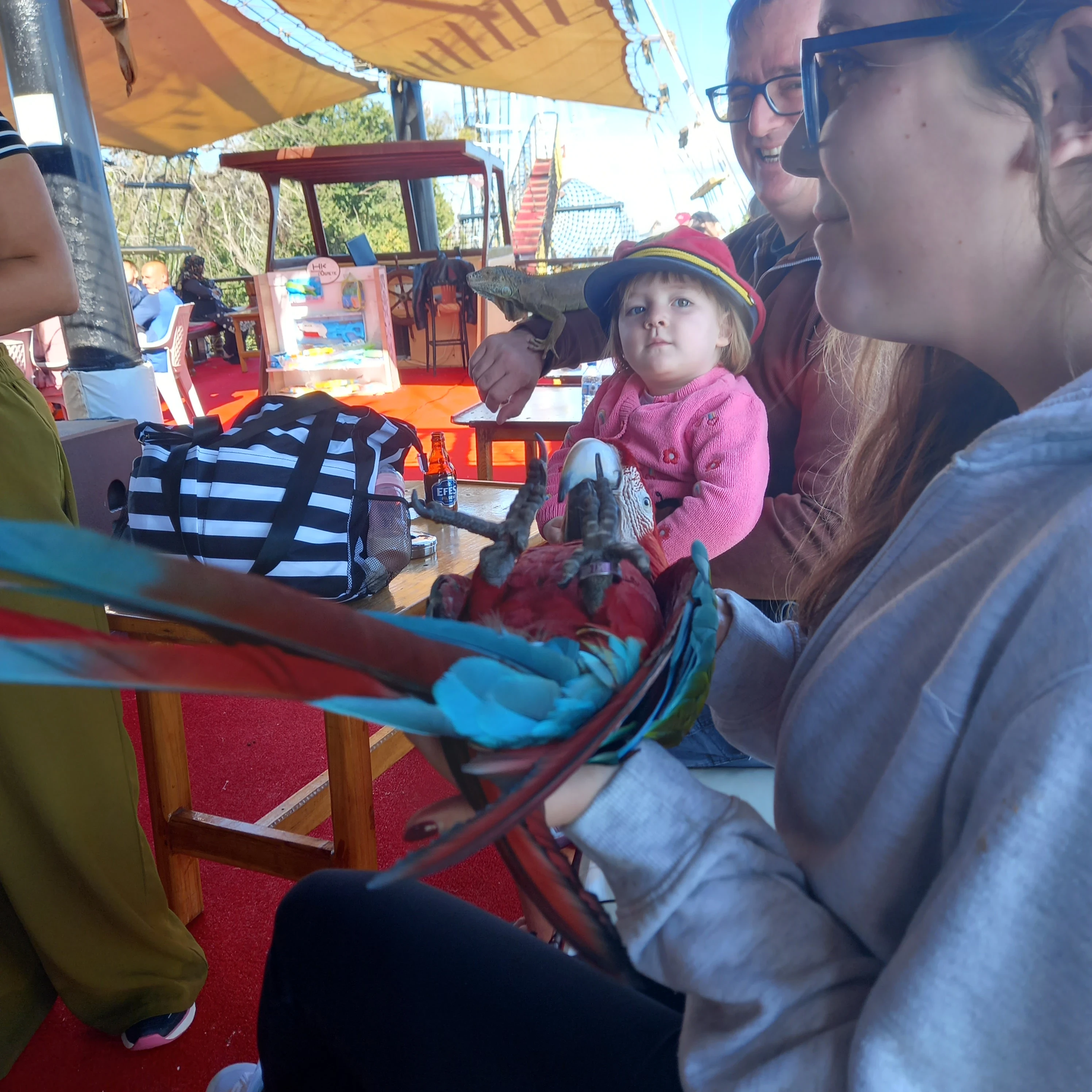 My nieces bethany and amilia holding a red macaw parrot and bearded dragon