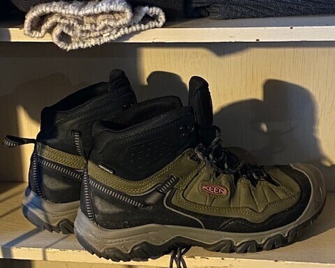 Keen hiking boots sitting on a pale-yellow shelf