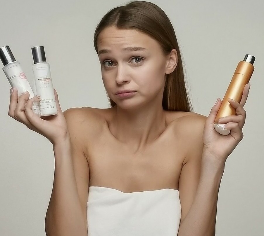 young lady holding skincare products in both hands shrugging shoulders
