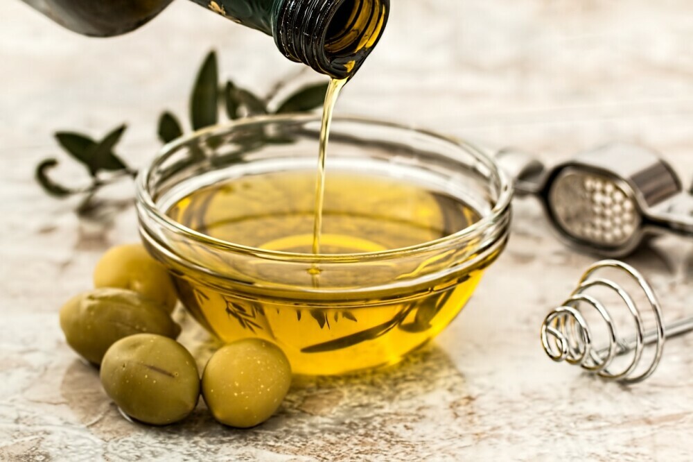 olive oil in a small glass bowl surrounded by olives