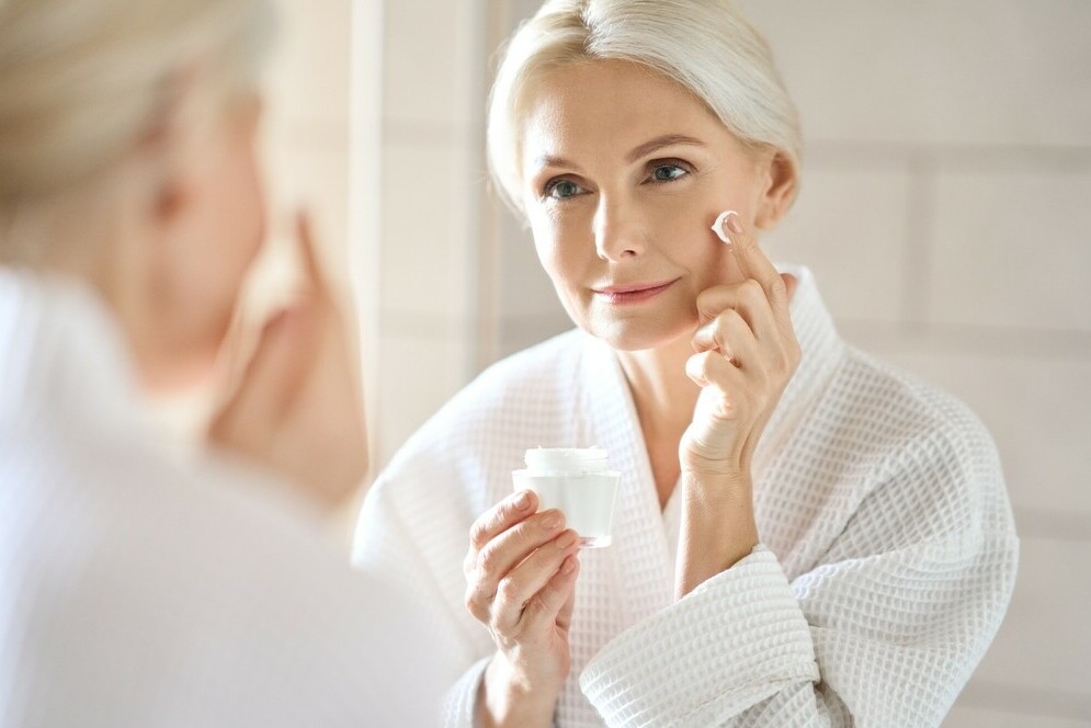 middle age lady looking in mirror applying skincare