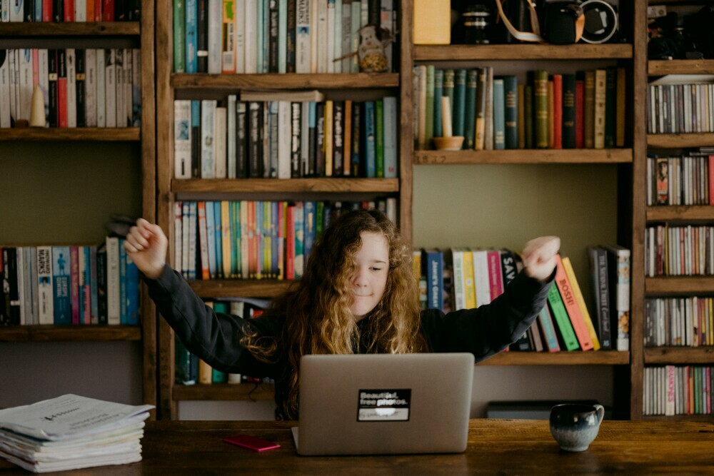 girl working on laptop with arms in the air