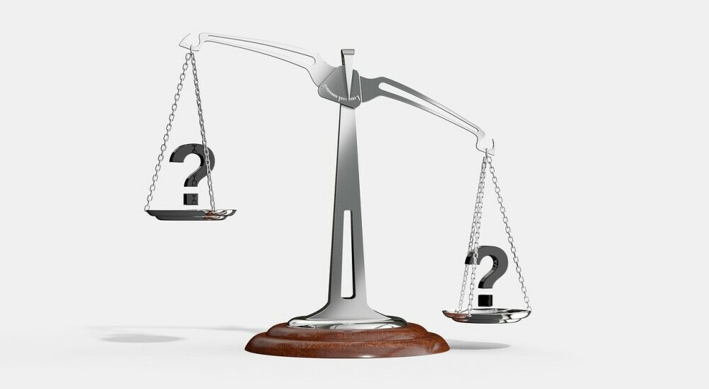 Image is of a scale weighing question marks for choices 