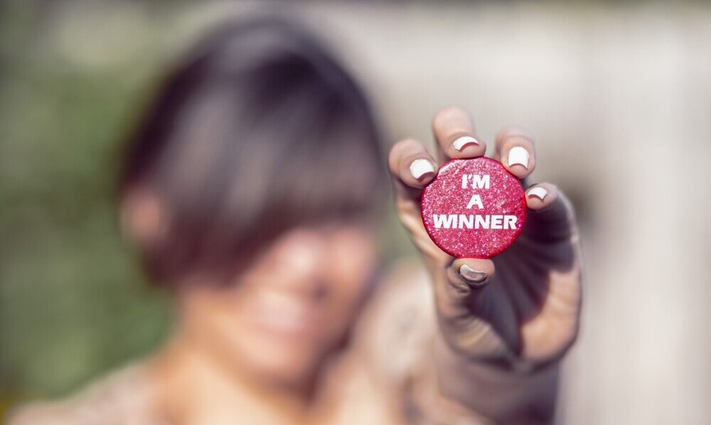 Woman holding a button saying i am a winner