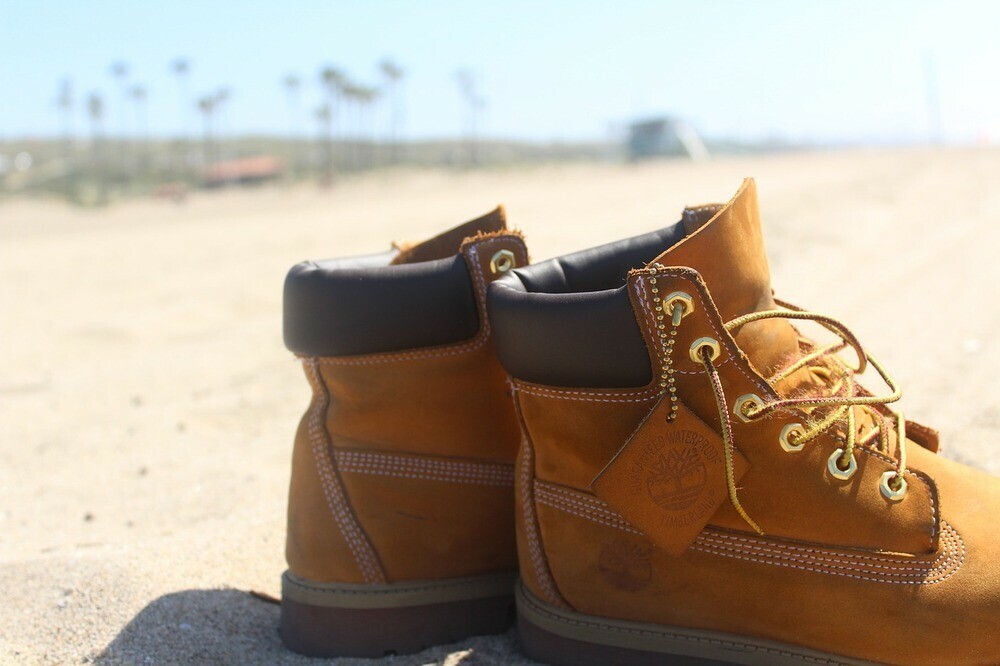 Timberland tanned laced boots placed on a beach on a sunny day