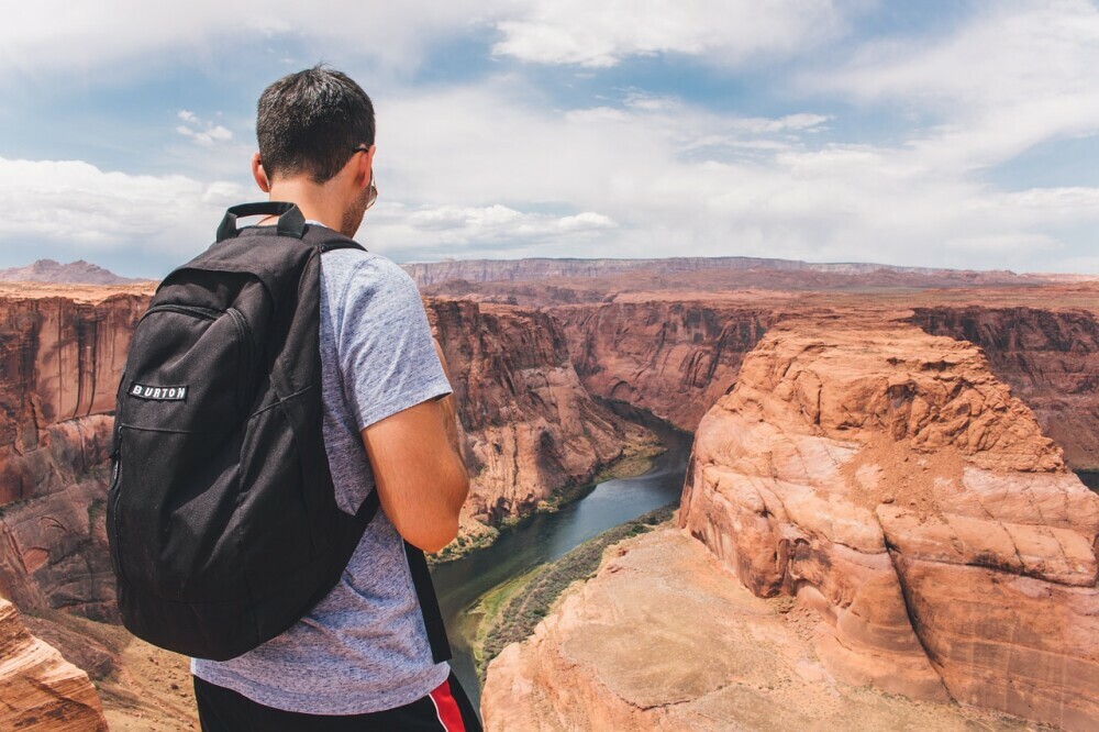 Individual wearing a black rucksack overlooking the grand canyon