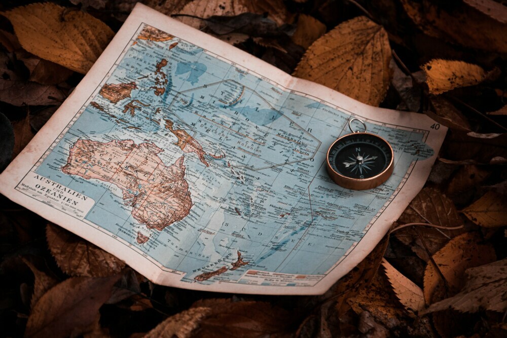 Image of a map and compass placed on top of leaves on the ground