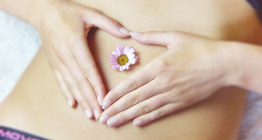 Image of a woman's abdomen with a flower, representing digestive health