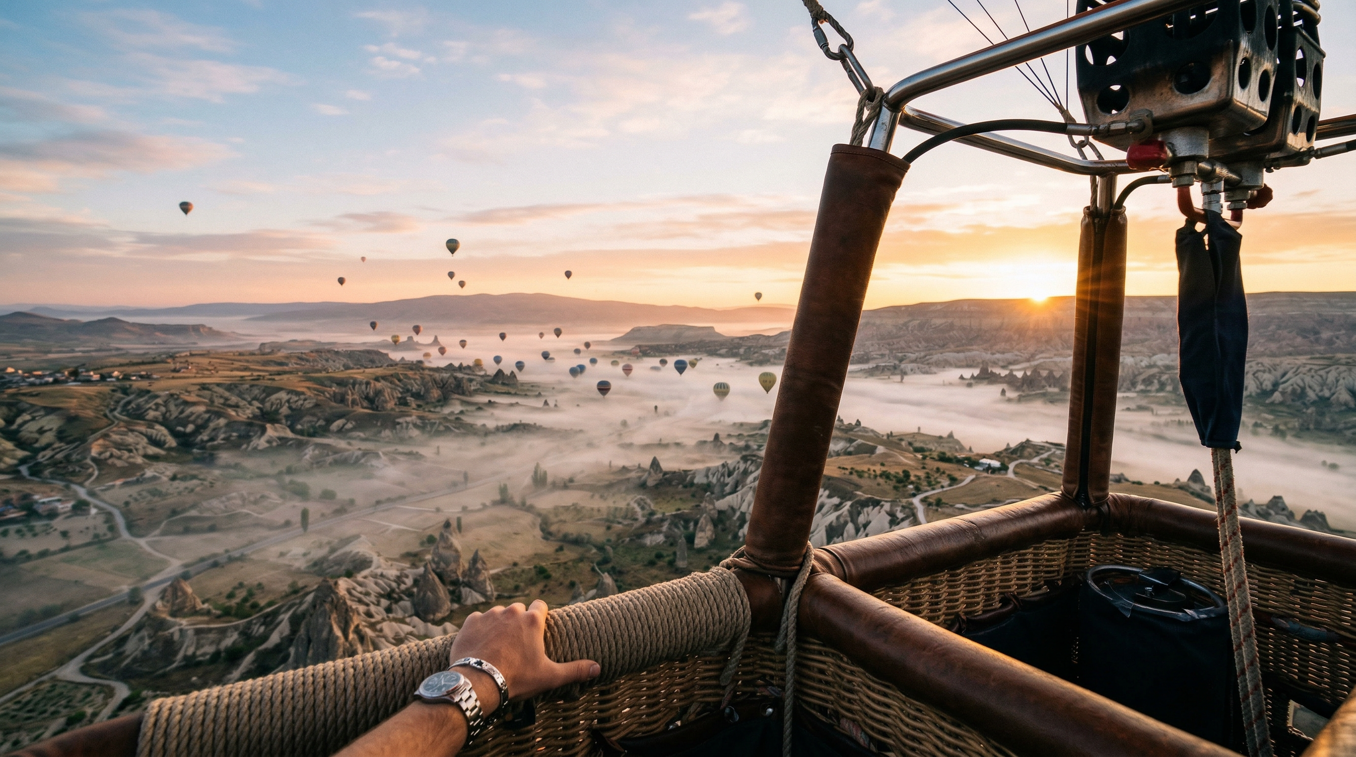 View from a hot air balloon basket over valleys and sunrise mist