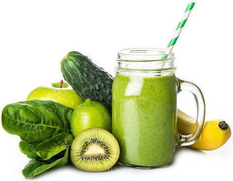 Revitalise And Refresh The Ultimate Detox Green Smoothie image 1 green smoothie in glass jar with sevral ingredients surrounding it including kiwi banana spinach leave lime apple cucumber frosted fusions