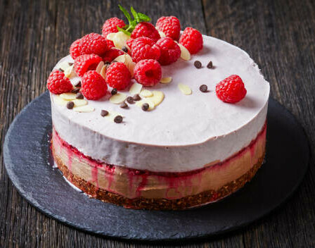 Learn How To Make Homemade Ice Cream Cakes image 6 homemade ice cream cake showing layers of cake and ice cream and topped with fresh raspberries almonds and chocolate frosted fusions