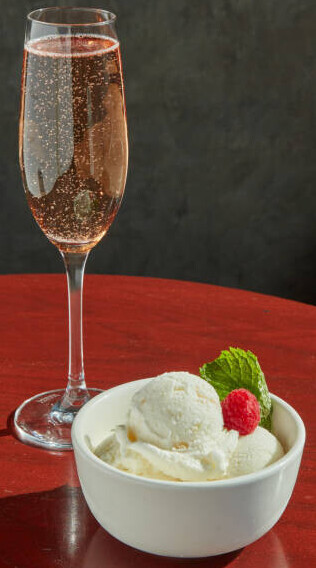 Prosecco And Strawberry Ice Cream Recipe For Your New Year's Celebrations! image 1 flute of prosecco next to a dish of ice cream topped with a strawberry and green leaves frosted fusions