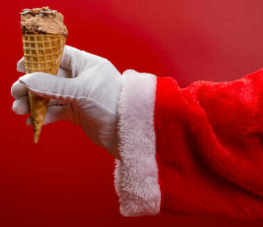 Festive Homemade Ice Cream Flavours for a Cosy and Delicious Christmas image 3 outstretched santa arm holding an ice cream cone red background frosted fusions