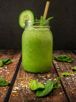 The Power Of Fat-Burning Smoothies image 4 Green smoothie with spinach leaves scattered around slice of cucumber dark wooden background frosted fusions