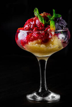 Halloween Ice Cream Treats - Spooky Ice Scream Recipes For The Occasion image 5 tall glass of blood roange sorbet with red sauce drizzled all over black background frosted fusions