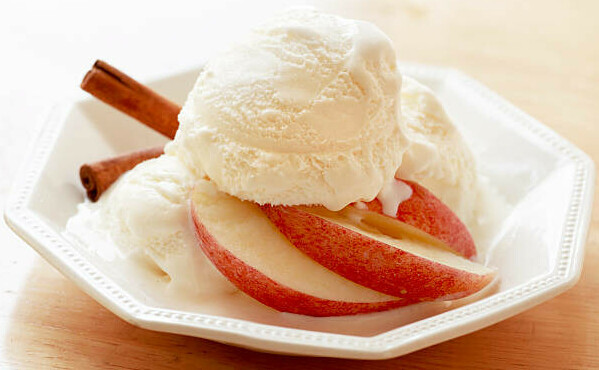 Spiced Apple Homemade Ice Cream A Twist on a Classic Pie Favourite image 5 Scoop of ice cream on white dish with fresh apples and cinnamon sticks frosted fusions