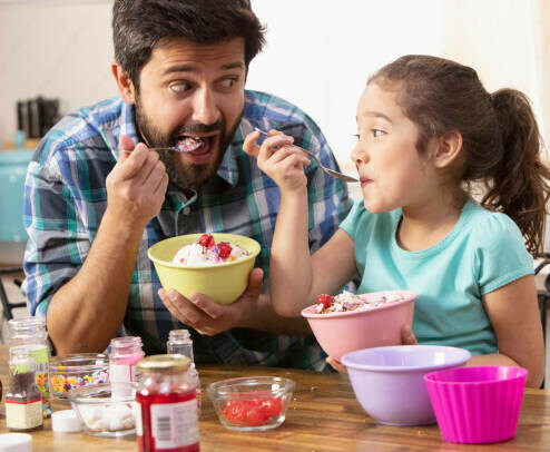 Unique Homemade Ice Cream Recipes image 3 father and daughter smiling eating ice cream together with an array of ingredients frosted fusions