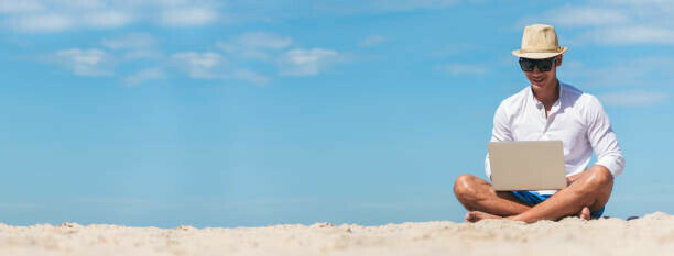 How To Choose Profitable Affiliate Niches image 2 man sat crossed legged on a beach with laptop blue skies and sand make xtra money online