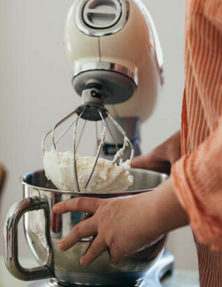 Why Is My Homemade Ice Cream So Hard image 5 person holding a stand mixer with cream mixed to stiff peaks frosted fusions