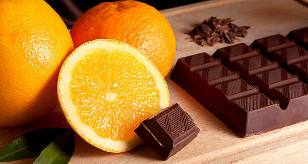 Taste the Nostalgia Terry's Chocolate Orange Homemade Ice Cream image 3 oranges whole and halved with leaves and a slab of chocolate on wooden board frosted fusions
