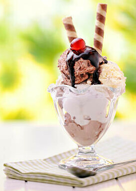Classic Ice Cream Desserts image 6 ice cream sundae in a dessert glass with edible straws chocolate sauce drizzled and a cherry on top frosted fusions