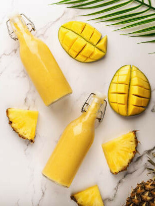 The Power Of Fat-Burning Smoothies image 6 fresh pineapple and mango with glass bottles of yellow smoothie frosted fusions