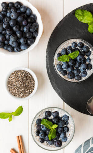 Benefits Of Using Superfoods In Homemade Ice Creams image 2 bowls filled with blueberries and chia seeds with cinnamon sticks and mint leaves frosted fusions