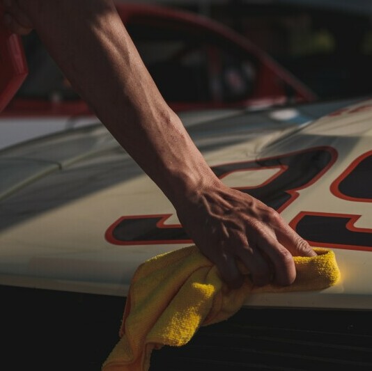 a hand polishing a car with a rag