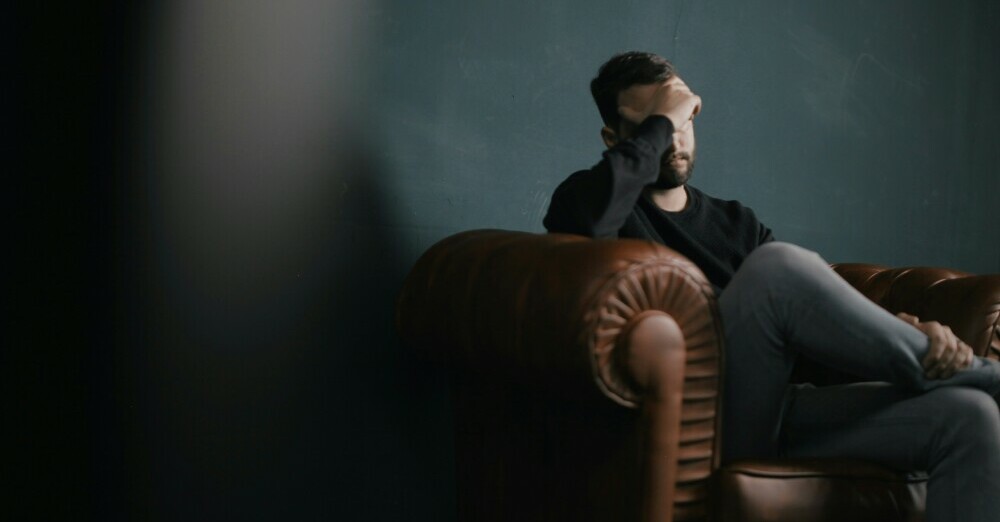 Guy sitting in a couch feeling sad 